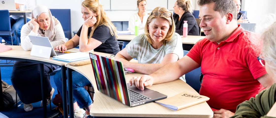 Trainer geeft persoonlijke uitleg aan een deelnemer achter de laptop