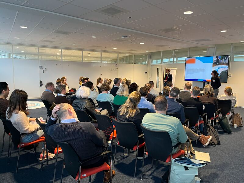 Groep medewerkers volgt een plenaire training met een presentatiescherm