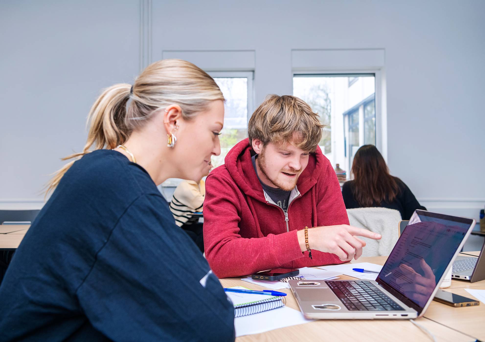 Trainer helpt een deelnemer met zijn laptop tijdens een computertraining